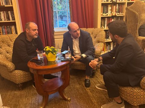 Three men in conversation around a small table in a library
