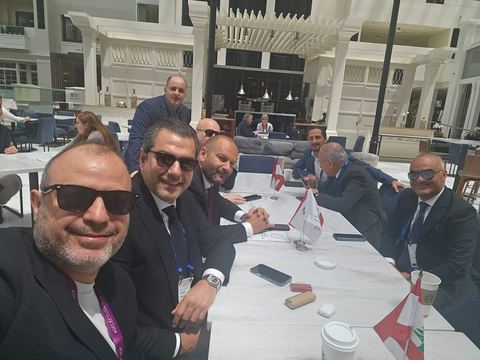 Delegates at a long table with small Lebanese flags