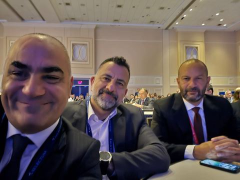 Three delegates seated in a ballroom