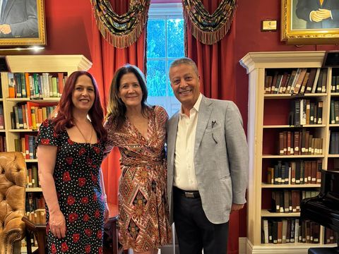 Three guests posing in a library with red walls