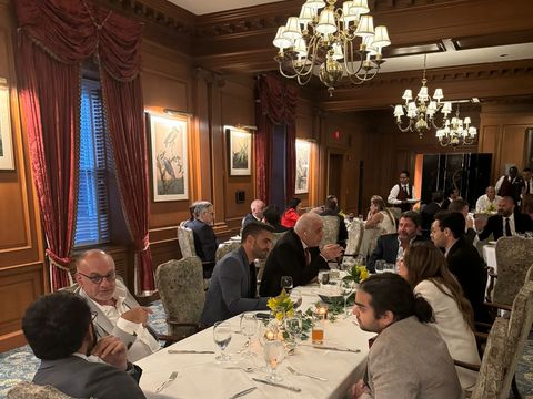 Guests seated at a long dining table in a wood-paneled room