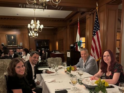 Four guests seated at a dinner table with U.S. and Lebanese flags and a LAB-C lectern