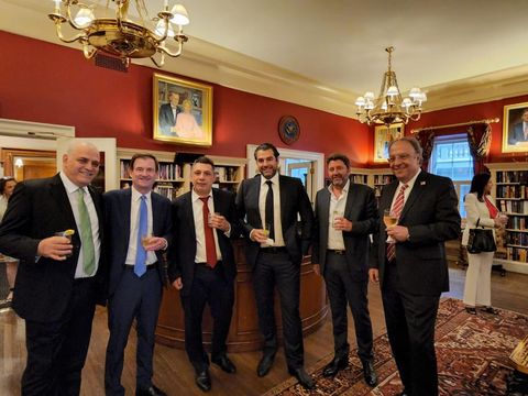 Six men with drinks at a reception