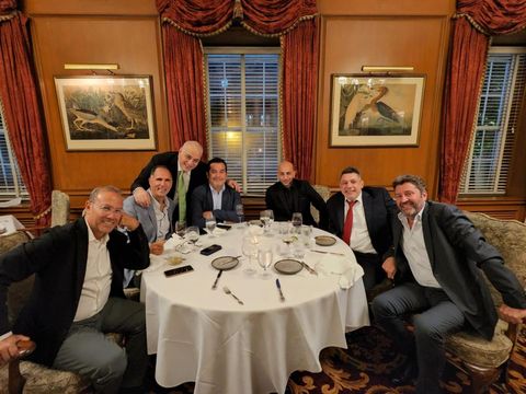 Seven men gathered around a round dinner table