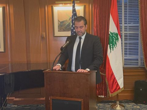 Speaker at a lectern beside the U.S. and Lebanese flags