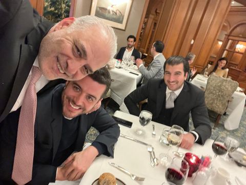 Three men smiling at a restaurant table, selfie view