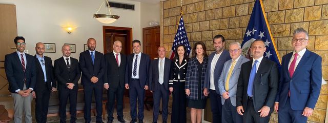 Delegation group photo in front of the U.S. flag and a stone wall